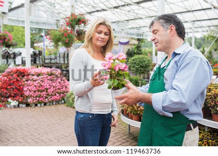 Woman talking to worker about plant in garden center