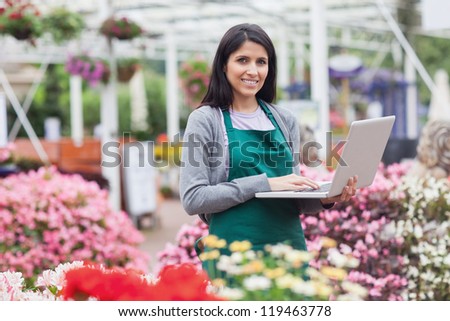 Woman using laptop in the garden center while smiling