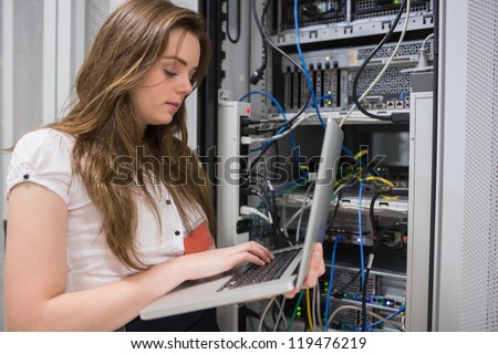 Woman using laptop to work on servers in data center