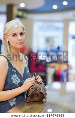 Woman holding handbag at counter in clothing store