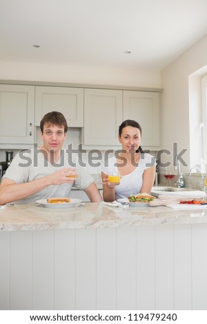 Two friends eating sandwiches and drinking juice in the kitchen