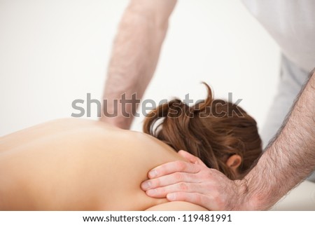 Doctor massaging the shoulders of woman while standing in a room