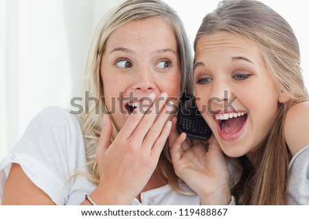 A pair of sisters smiling in happiness as they make a call