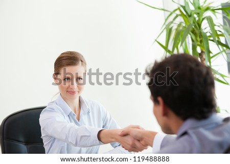Businesspeople looking each other while shaking hands in an office