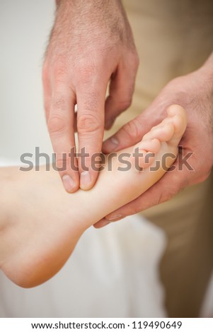 Two fingers palpating the muscles of a foot indoors