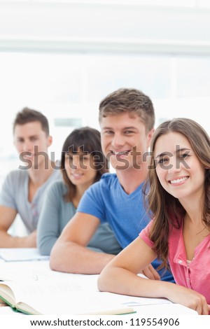 A smiling group of people looking into the camera and smiling with books in front of them