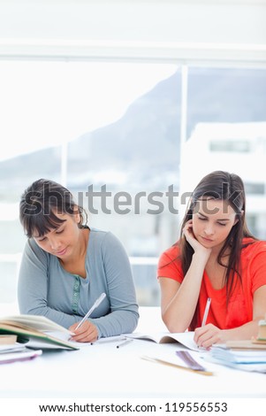 Two women studying hard looking at their books while sitting at the table