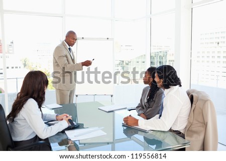 Businessman pointing to something on the flipchart to give explanations to his team