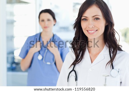 Young smiling nurse accompanied by a co-worker in the background