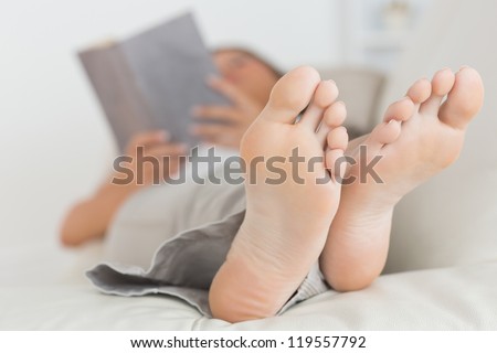 Woman with her feet up reading a book on the sofa