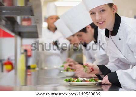 Happy chef looking up from preparing salad in culinary class