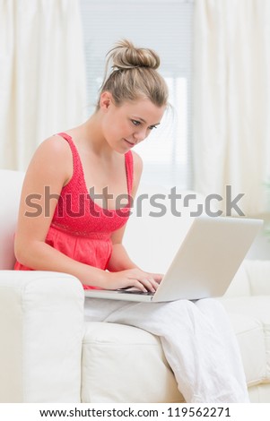 Woman concentrated in using laptop while sitting on the sofa