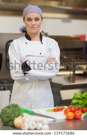 Serious chef standing beside chopping board and vegetables in the kitchen