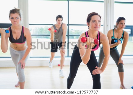 People lifting weights in aerobics class in fitness studio