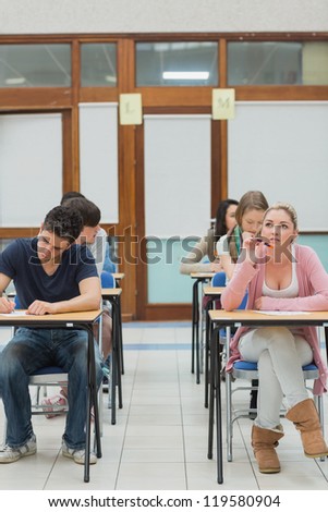 Students in an exam hall while one is thinking in college