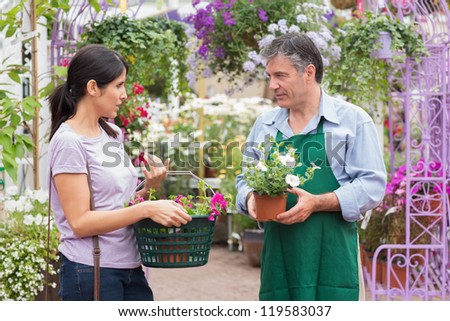 Customer talking to garden center worker about potted plants