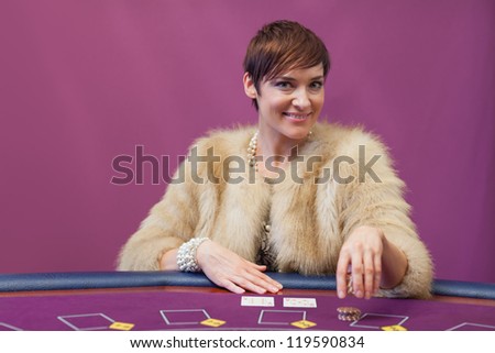 Woman sitting in a casino at table while stacking chips and placing cards