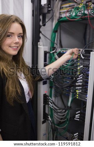 Smiling girl working on rack mounted servers in data storage facility