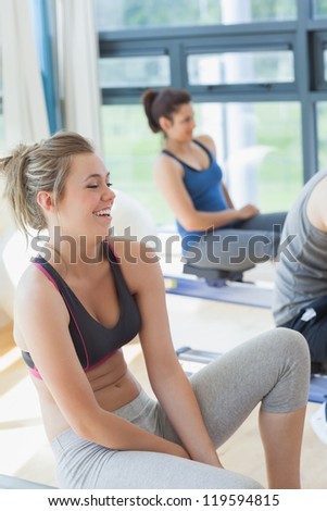 Woman sitting at the row machine at the gym laughing