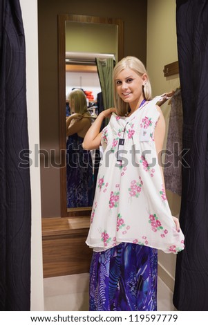 Woman standing on the changing room holding up dress
