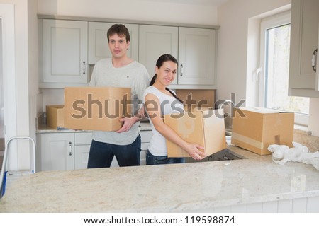Two young people standing in the kitchen and holding boxes for a relocation