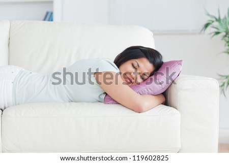Woman sleeping on a couch with a pillow in a living room