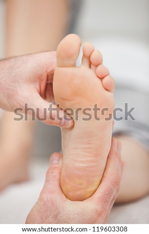 Doctor pressing the sole of a foot with his thumb in a room