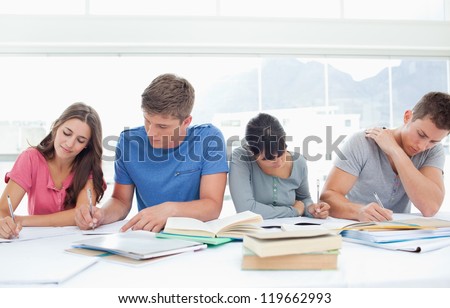 Four studying students sit beside each other and work hard