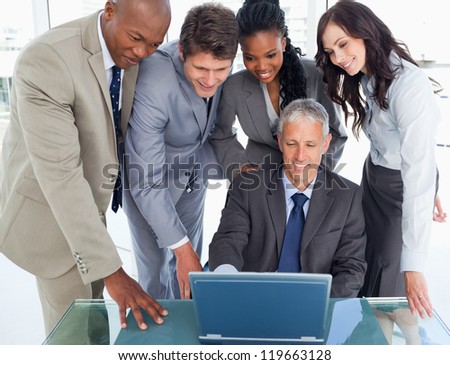 Young executives attentively listening to their mature manager behind the laptop