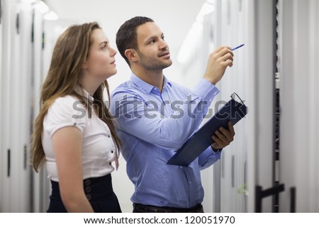 Technicians with clipbard looking at servers in data center