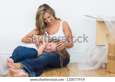 Daughter resting on the mother's legs on the floor