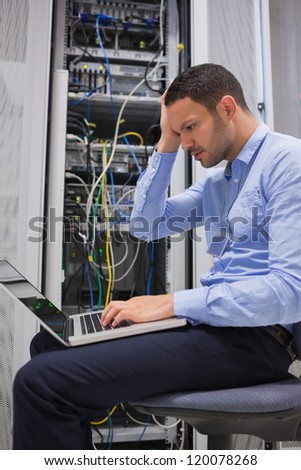 Data technician getting stressed over servers with laptop
