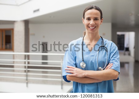 Smiling nurse with crossed arms in hospital corridor