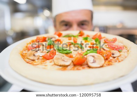 Cook presenting a mushroom pizza