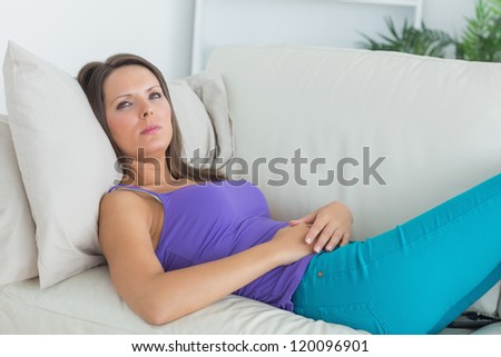 Serious woman lying on the sofa and looking away in the living room