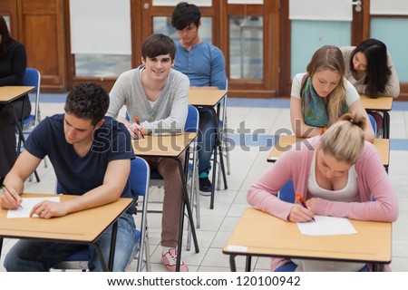 Students sitting in exam room with one boy looking up and smiling