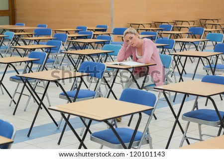 Student sitting and talking at desk in empty exam hall