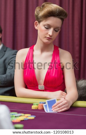 Woman sitting at table holding cards in her hands in casino