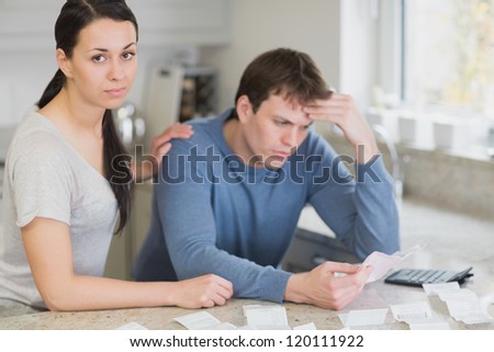 Two people in the kitchen calculating finances with calculator