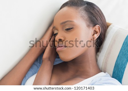 Sad black woman lying in a living room