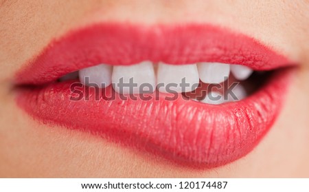 Close-up of the white teeth of a woman biting her lips