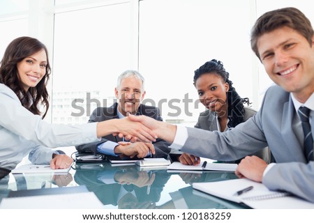 Young smiling executives shaking hands while looking at the camera