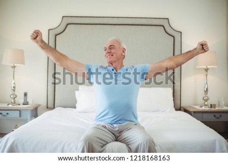 Senior man waking up in bed and stretching his arms