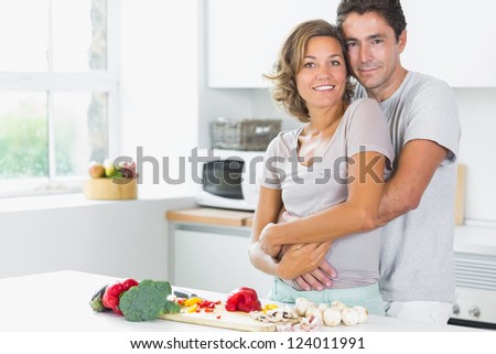 Wife and husband embracing in the kitchen buy the chopping board