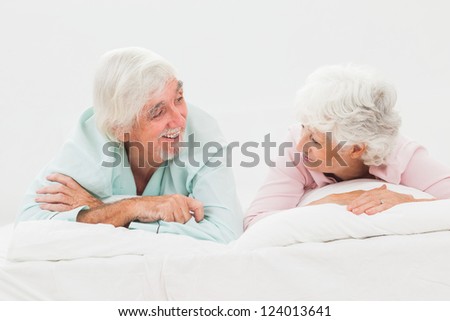Elderly happy couple looking at each other in bed