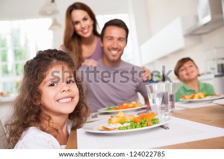 Family smiling at the camera at dinner table in kitchen
