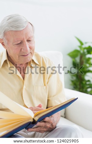 Elderly man watching his pictures on a sofa