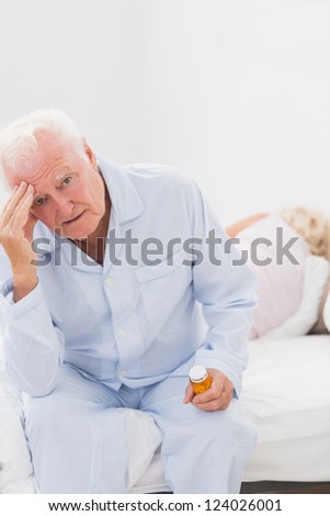 Elderly man suffering while woman sleeping on the bed