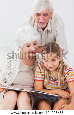 Smiling girl reading with grandparents on the couch