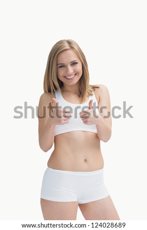 Portrait of happy young woman in sportswear gesturing double thumbs up over white background
